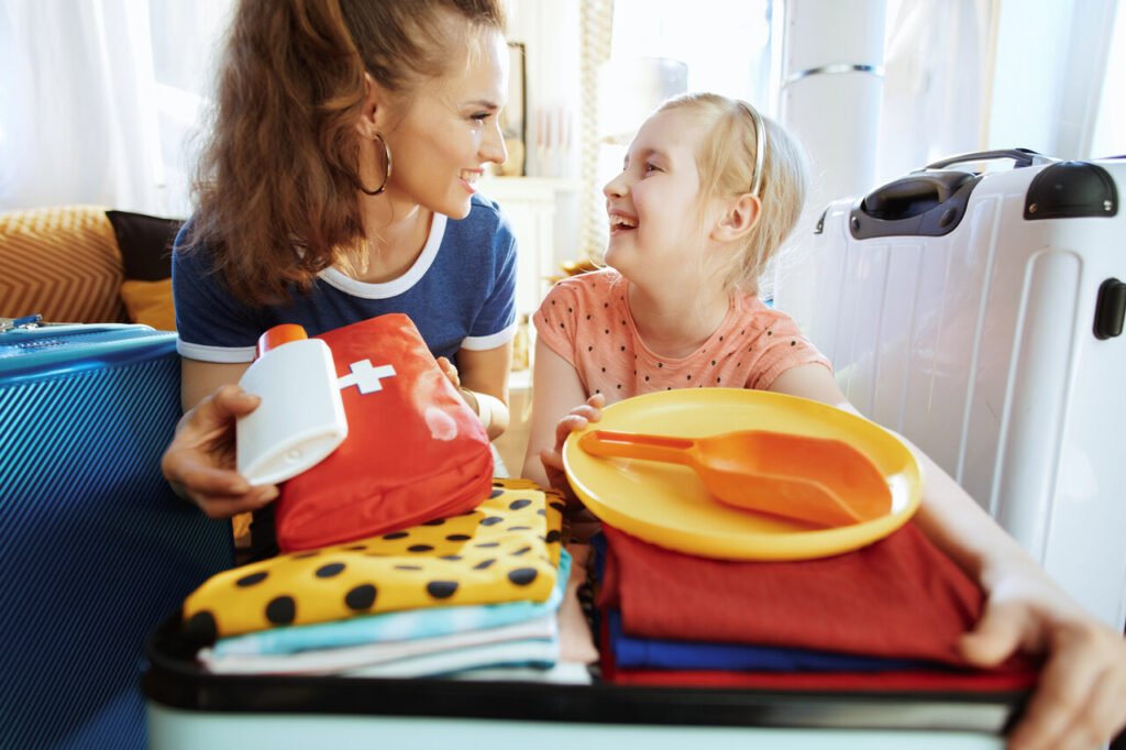 mama z córką wkładają do walizki apteczkę podróżną