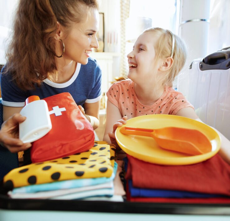 mama z córką wkładają do walizki apteczkę podróżną