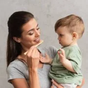 uśmiechnięta mama myje niemowlęciu zęby