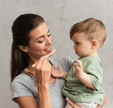 uśmiechnięta mama myje niemowlęciu zęby