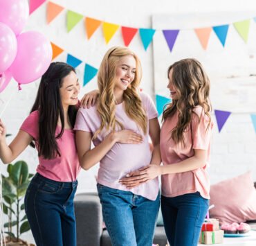 kobiety dotykają brzuch młodej mamy na baby shower