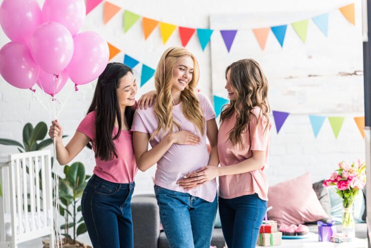 kobiety dotykają brzuch młodej mamy na baby shower