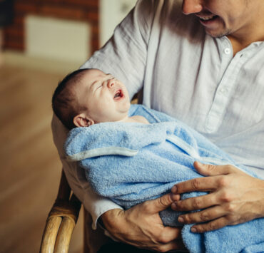 ojciec trzyma w ramionach noworodka