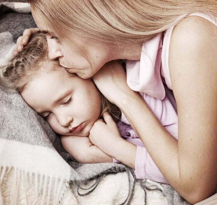 mama całuję dziecko w czoło, sprawdza czy ma gorączkę