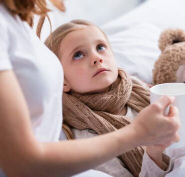 Mama daje chorej córce kubek herbaty