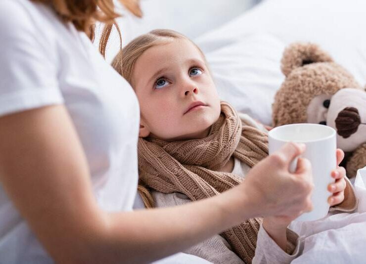 Mama daje chorej córce kubek herbaty