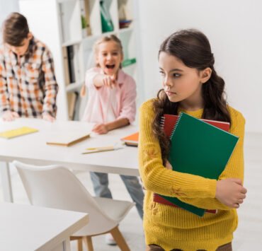 smutna dziewczynka, z któej naśmiewają się rówieśnicy