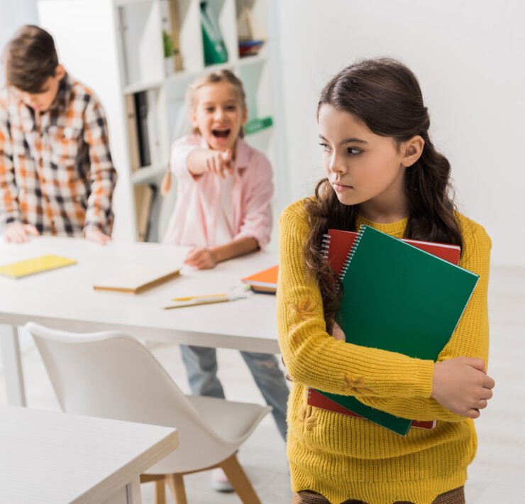 smutna dziewczynka, z któej naśmiewają się rówieśnicy