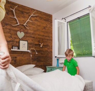 chłopiec pomaga mamie ścielić łóżko