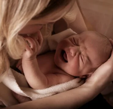 płaczącę niemowlę w ramionach mamy