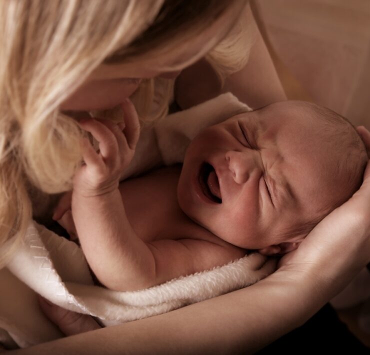 płaczącę niemowlę w ramionach mamy