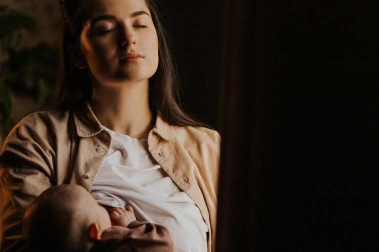 kobieta karmiąca dziecko na ciemnym tle