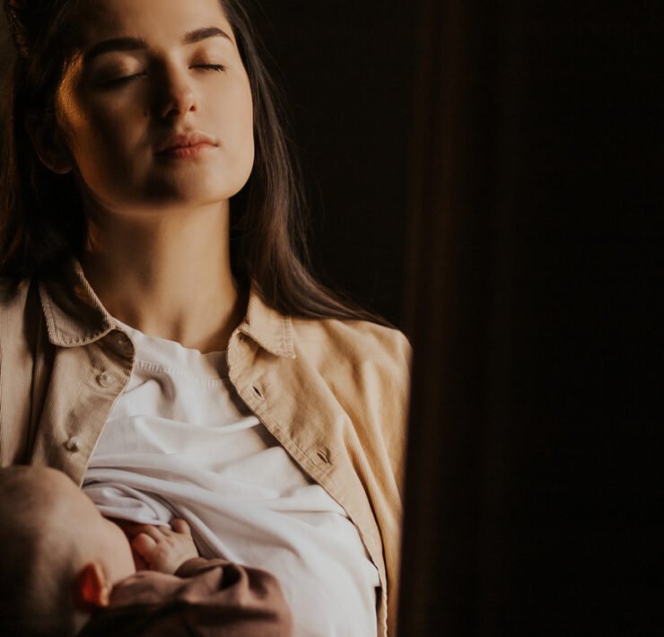 kobieta karmiąca dziecko na ciemnym tle