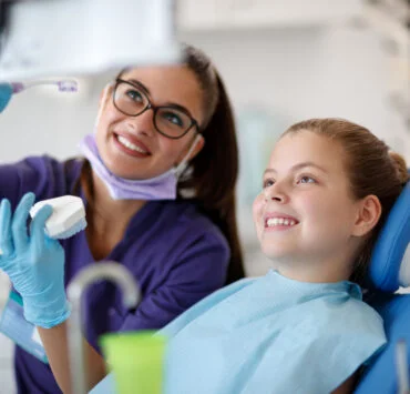 uśmiechnięta ortodontka z dzieckiem