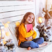 Dziewczyna w bożonarodzeniowej scenerii tuli książkę
