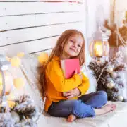 Dziewczyna w bożonarodzeniowej scenerii tuli książkę