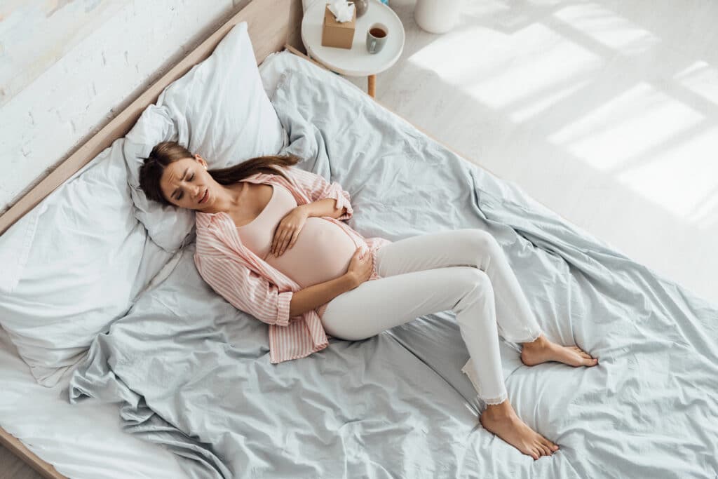 widok z góry na kobiet w ciąży, którą boli podbrzusze