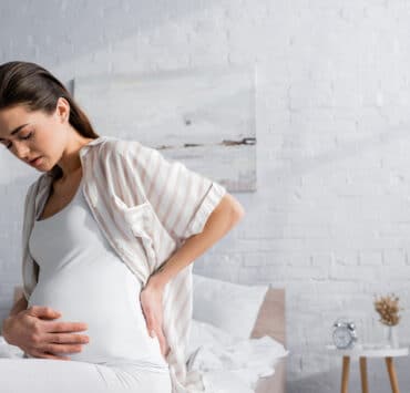 kobieta w ciąży trzyma się za brzuch, bo boli ją podbrzusze