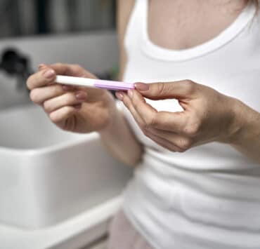 kobieta w łazience trzyma test ciążowy