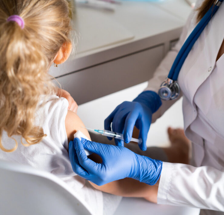 pielęgniarka podaje dziewczynce szczepionkę w ramię