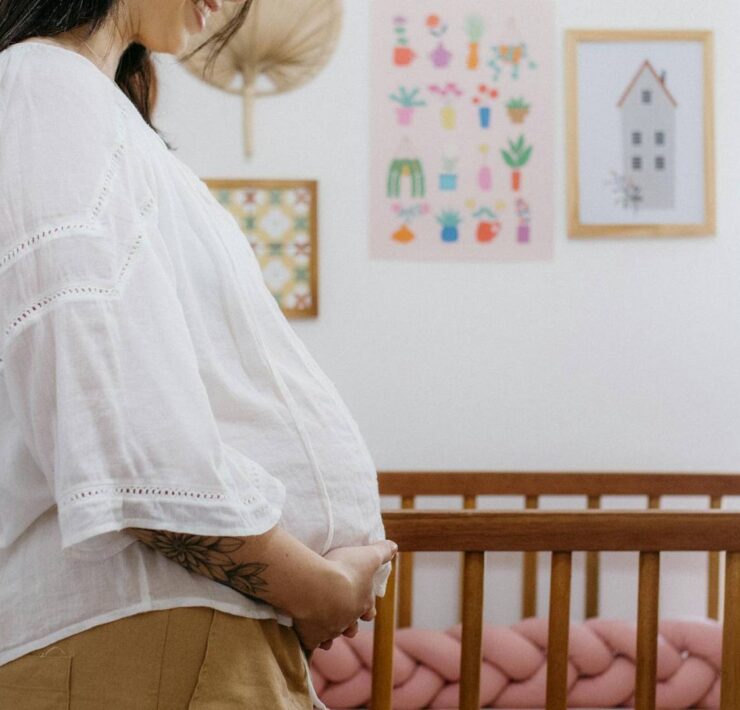 Kobieta w ciąży stoi obok łóżeczka dziecięcego