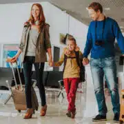 rodzina trzyma się za ręce na lotnisku z bagażem i dokumentami (paszport)