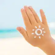 Dłoń dziecka z narysowanym kremem z filtrem przeciwsłonecznym słońcem – ochrona skóry przed słońcem na plaży.