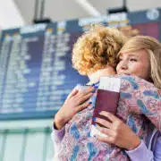 Dziecko z paszportem żegna się na lotnisku — zgoda na wyjazd dziecka za granicę jako dokument niezbędny przy podróży z opiekunem.