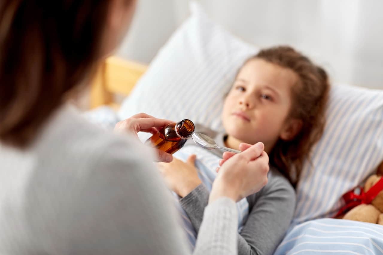 mama, której przyznano zasiłek opiekuńczy na dziecko podaje córce leki w czasie choroby