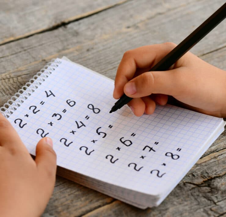 dziecko uczy się tabliczki mnożenia zeszyt z działaniami, które liczy dziecko