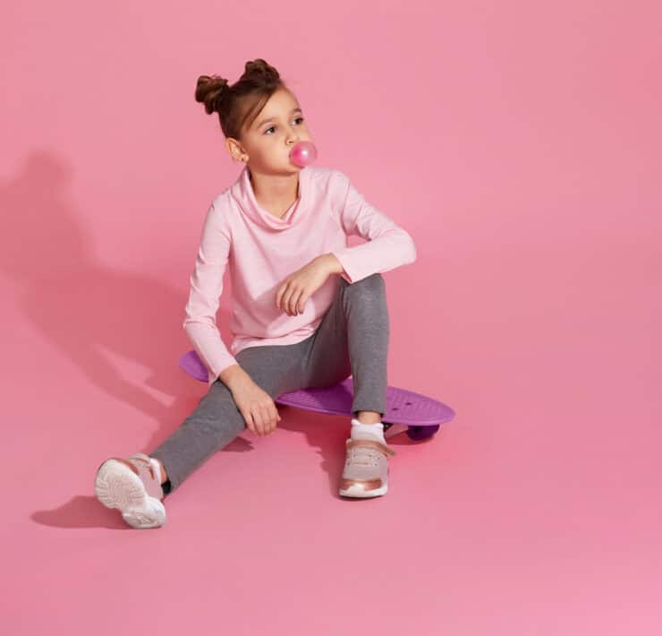 dziewczynka z gumą do żucia na różowym tle