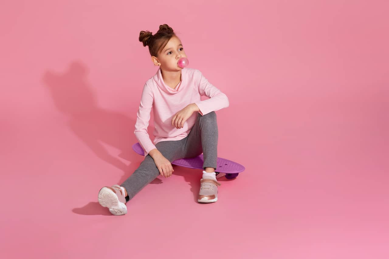 dziewczynka z gumą do żucia na różowym tle