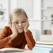 przebodźcowana dziewczynka zmęczona siedzi nad książkami